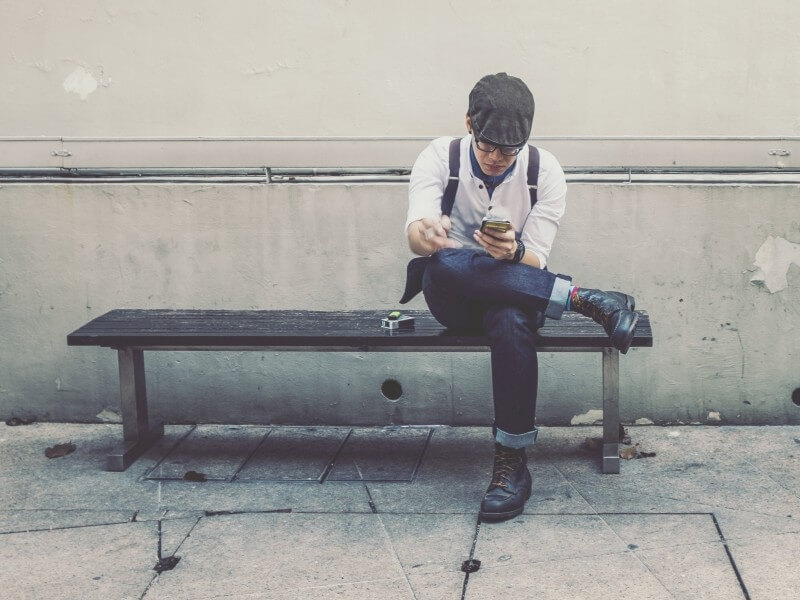 fashionable-man-using-mobile-phone-on-bench