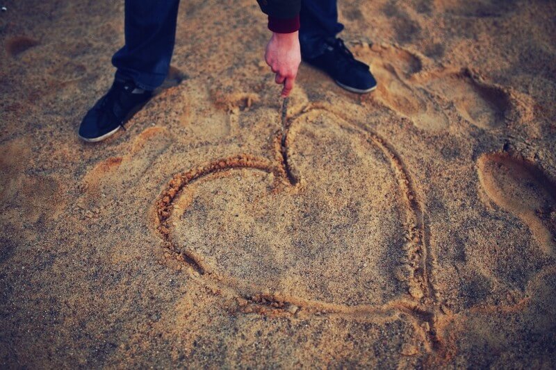 man-drawing-heart-in-sand