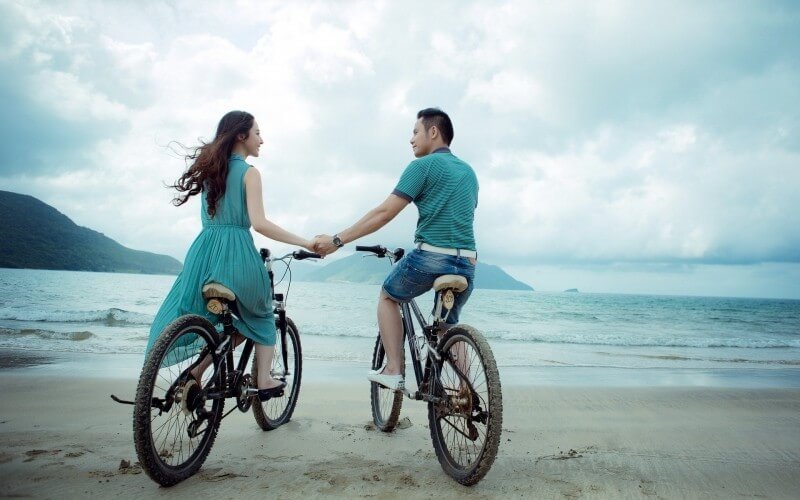young-couple-with-bicycles-holding-hands-on-beach